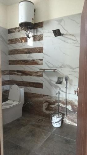a bathroom with a toilet and a wall with stripes at Roshni Apartment - Ground Floor in Vishāram
