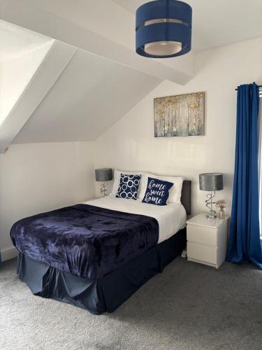 a bedroom with a large bed with blue curtains at Crosby Apartments in Liverpool