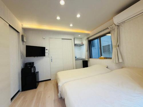 a hotel room with two beds and a television at SnowMapleHouse西川口 in Kawaguchi