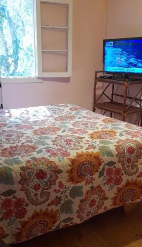 a bedroom with a bed with a flowered blanket and a television at Cabaña La Isla in Isla Negra