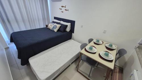 a small bedroom with a bed and a small table at Studio Mare Alta in Tamandaré