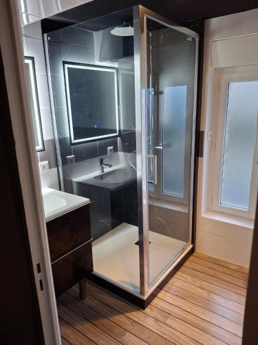 a bathroom with a glass shower and a sink at La parenthèse secrète in Danvou