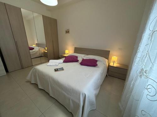a bedroom with a large white bed with purple pillows at Il Mare a due Passi in Pesaro