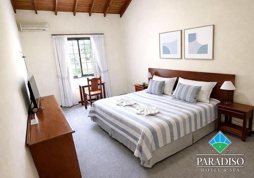 a bedroom with a bed and a desk and a television at Paradiso Hotel & Spa in Merlo