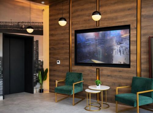 a lobby with two chairs and a tv on a wall at Hotel Mirage Brooklyn in Brooklyn
