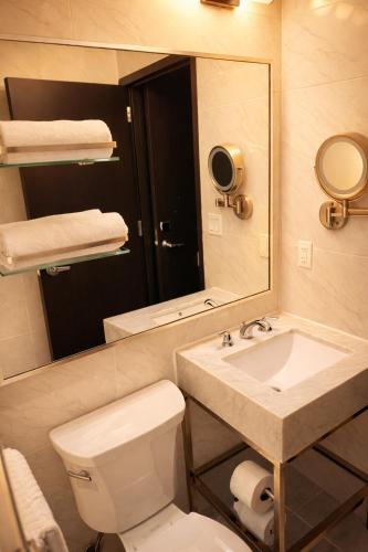 a bathroom with a sink and a toilet and a mirror at Hotel Mirage Brooklyn in Brooklyn