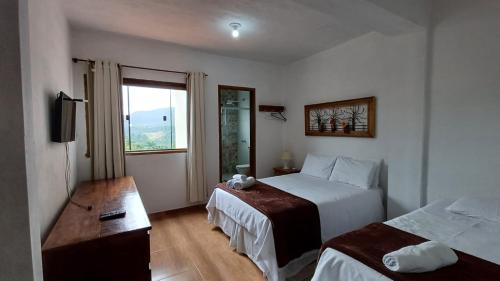 a hotel room with two beds and a window at Pouso Flor da serra in Tiradentes