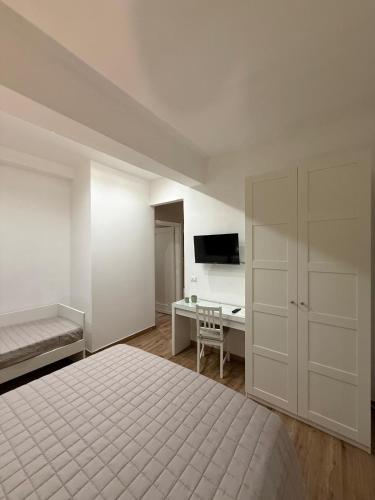 a white bedroom with a bed and a desk at Titti's Nest in Casteldaccia