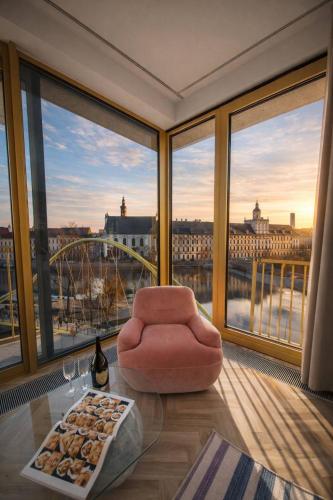 a living room with a chair and large windows at Boulevard Drobnera SPA&Wellness - Restaurant PONTI - Widok na Odre in Wrocław