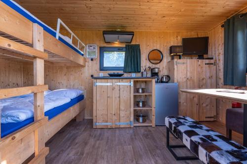 a bedroom with bunk beds and a kitchen in a cabin at Tinyhouse Spiegelpeer in Ruinerwold