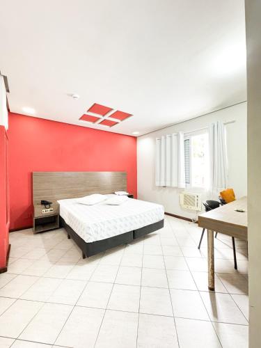 a bedroom with a bed and a red wall at Golfinho Hotel in São Vicente