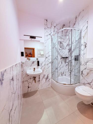 a bathroom with a shower and a toilet and a sink at City Tour Apartamenty in Poznań