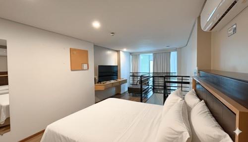 a hotel room with a bed and a television at Duplex com Banheira no Centro de Campo Grande in Campo Grande