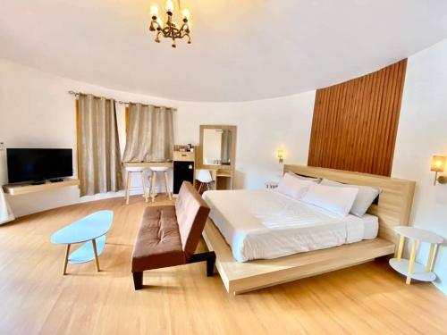 a bedroom with a bed and a chair and a television at Tropical pool villa คอฟฟี่มีเขาสาขา2 in HHQ