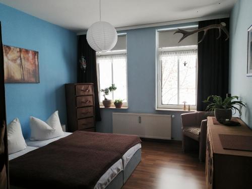 a bedroom with a bed and a couch and two windows at Ferienwohnung HARZgeNUSS in Wernigerode