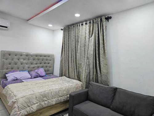 a bedroom with a bed and a couch at Hen-Cap Apartment Services in Agege
