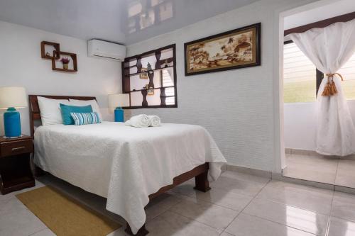 a bedroom with a bed with a white blanket and a window at Puerto Plata Home in San Felipe de Puerto Plata