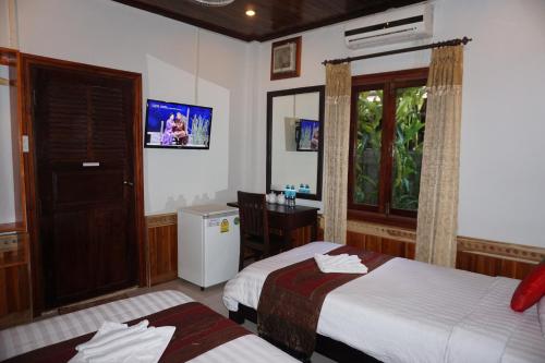 a bedroom with two beds and a desk and a mirror at Golden Lotus Place in Luang Prabang