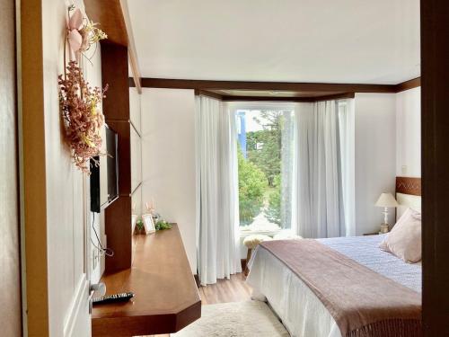 a bedroom with a bed and a large window at Suíte Refúgio Mountain Village Laje de Pedra 3003 in Canela