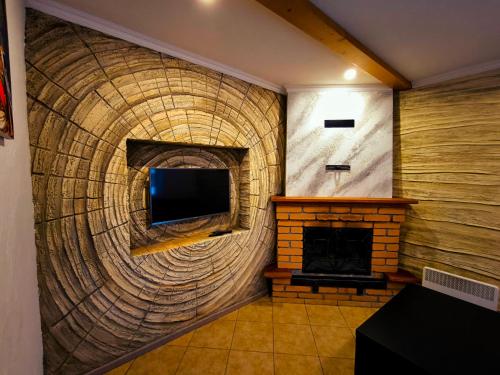 a living room with a brick fireplace and a television at садиба Пан Коцький in Kosiv