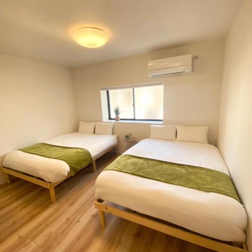 two beds in a small room with a window at AJITO Hostel 別館2 in Shingū