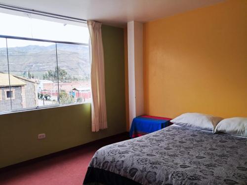 a bedroom with a bed and a large window at Belen Achomani in Chivay