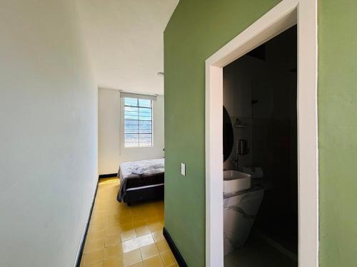 ein Badezimmer mit einer grünen Wand und einem Waschbecken in der Unterkunft Hostal Capullode Seda in Zapatoca