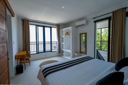 a bedroom with a large bed and large windows at Virgo Sun House in Uluwatu