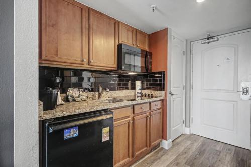 a kitchen with wooden cabinets and a black dishwasher at Carolinian Beach Resort in Myrtle Beach