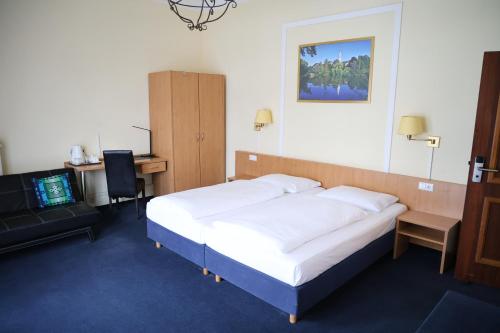 a bedroom with a bed and a desk and a tv at Hotel Villa Kisseleff in Bad Homburg vor der Höhe