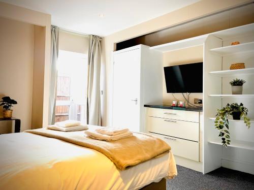 a bedroom with a large bed with a tv on it at Wessex House in Basingstoke