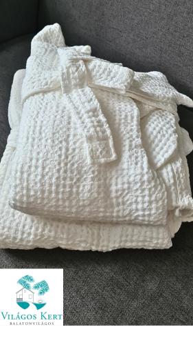 a white knitted blanket is sitting on the floor at Világos Kert Oliva House Steam in Balatonvilágos