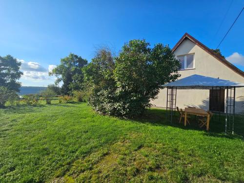 a house with a blue awning next to a yard at Poddasze nad jeziorem Piaski in Wolin