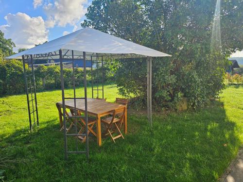 a table and chairs under a tent in the grass at Poddasze nad jeziorem Piaski in Wolin