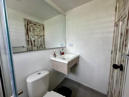 a white bathroom with a toilet and a sink at Hotel Casa La Macana in Macanal