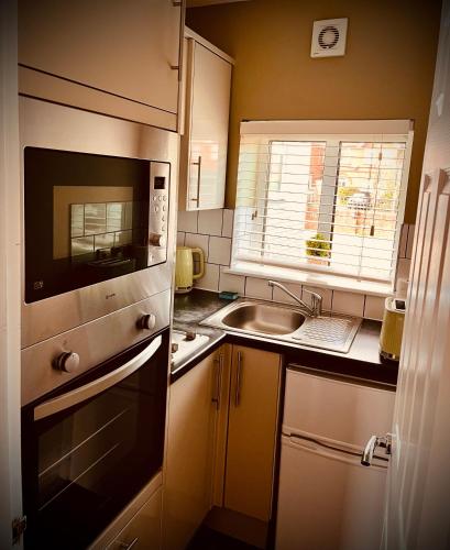 a small kitchen with a sink and a microwave at Wessex House in Basingstoke