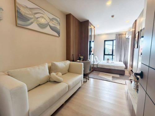 a living room with a white couch and a bedroom at The Cust Phuket in Ban Khok Chang