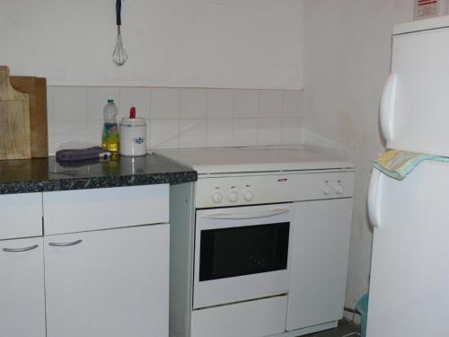une cuisine avec une cuisinière blanche et un réfrigérateur dans l'établissement la Laverie, à Allonnes