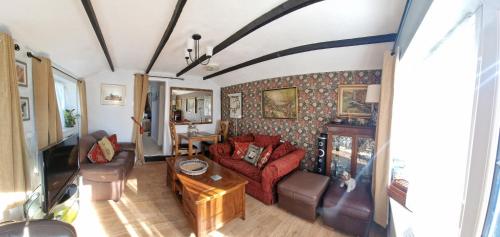 a living room with a couch and a table at The Old Dairy, comfy 1 bedroom apartment with lounge,bathroom and kitchenette near town, pubs and walks in Ringwood