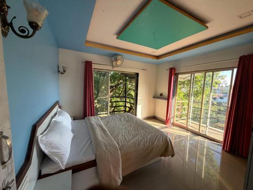 a bedroom with a bed and a large window at Mist Leaf Villa Mahabaleshwar in Mahabaleshwar