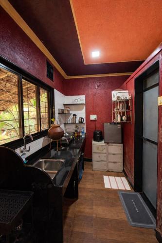 a kitchen with red walls and a kitchen with a sink at Mangalmurti Farmstay in Pendur