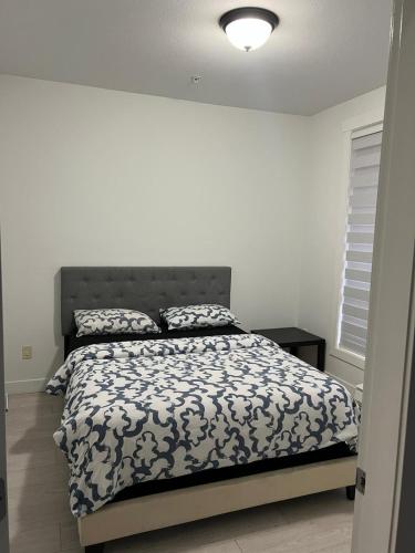 a bedroom with a bed with a black and white comforter at 2 Bedroom plus den 2 Bathroom apartment in Surrey