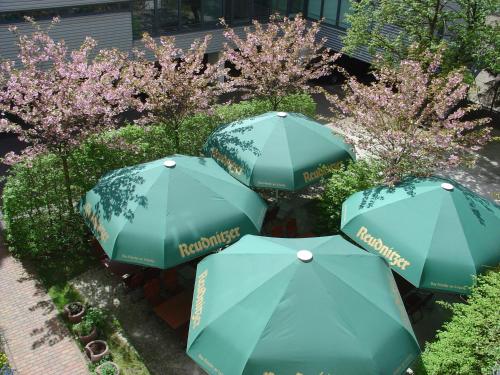 a group of blue umbrellas in a garden with trees at Galerie Hotel Leipziger Hof in Leipzig