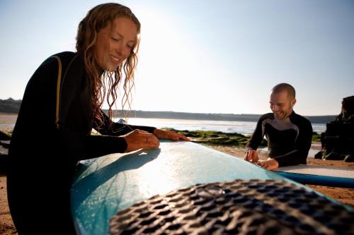 two surfers sitting on the beach with their surfboards at Stylish Central Famouth Studio with Parking | WiFi | in Falmouth