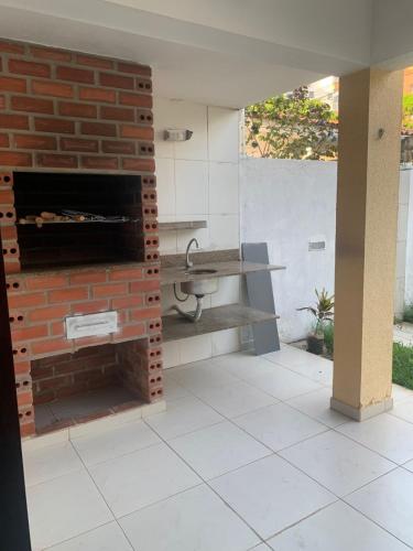 a kitchen with a brick fireplace and a sink at Pousada e Hostel Praia do poço in Cabedelo