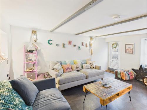 a living room with a couch and a table at Cosy Cornish Cottage with Firepit & Parking in Newlyn East