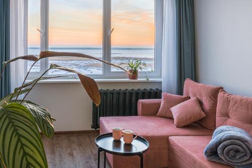 a living room with a pink couch and a view of the ocean at Lake View stay, stunning sunrises & free parking in Liepāja