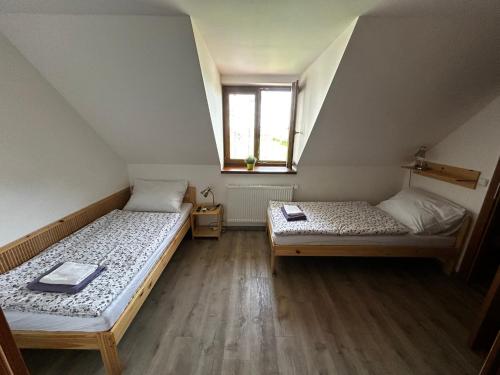 two beds in a small room with a window at Penzion U Ježka in Nedakonitz