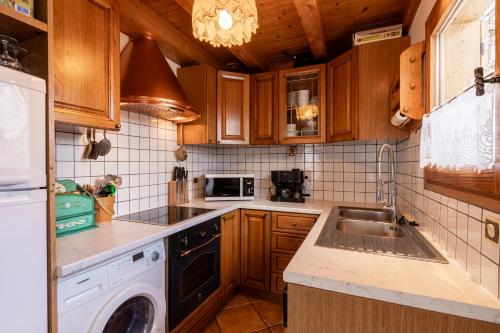 kuchnia z drewnianymi szafkami, zlewem i zmywarką w obiekcie Chalet Savoyard w mieście Clusaz