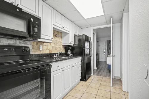 a kitchen with white cabinets and a black appliances at Ocean Park Resort in Myrtle Beach